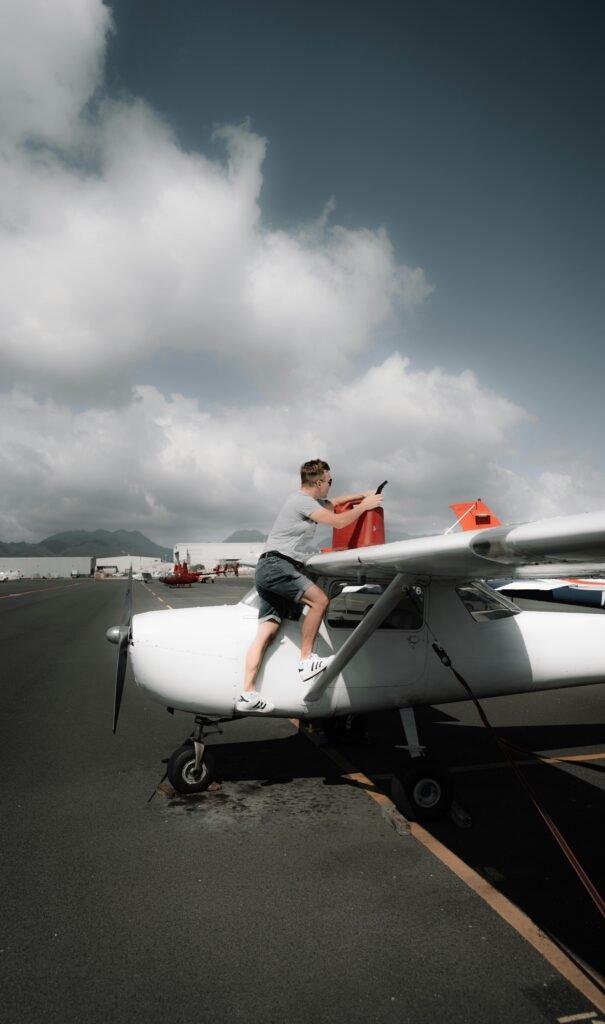Person refueling a light aircraft on a sunny day at an airport.